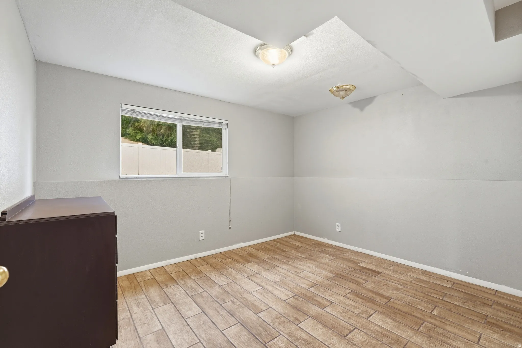 Room featuring wood-finish flooring, light gray walls, and a window with natural light