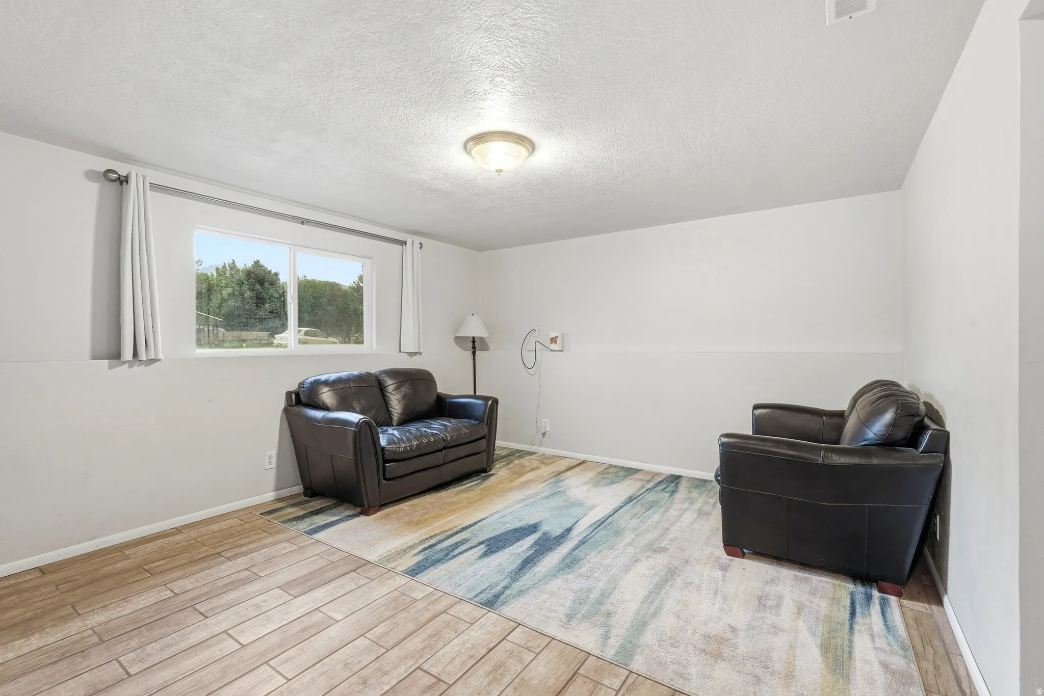 Bright room featuring a window with outdoor scenery, recessed lighting, and wood-finish flooring