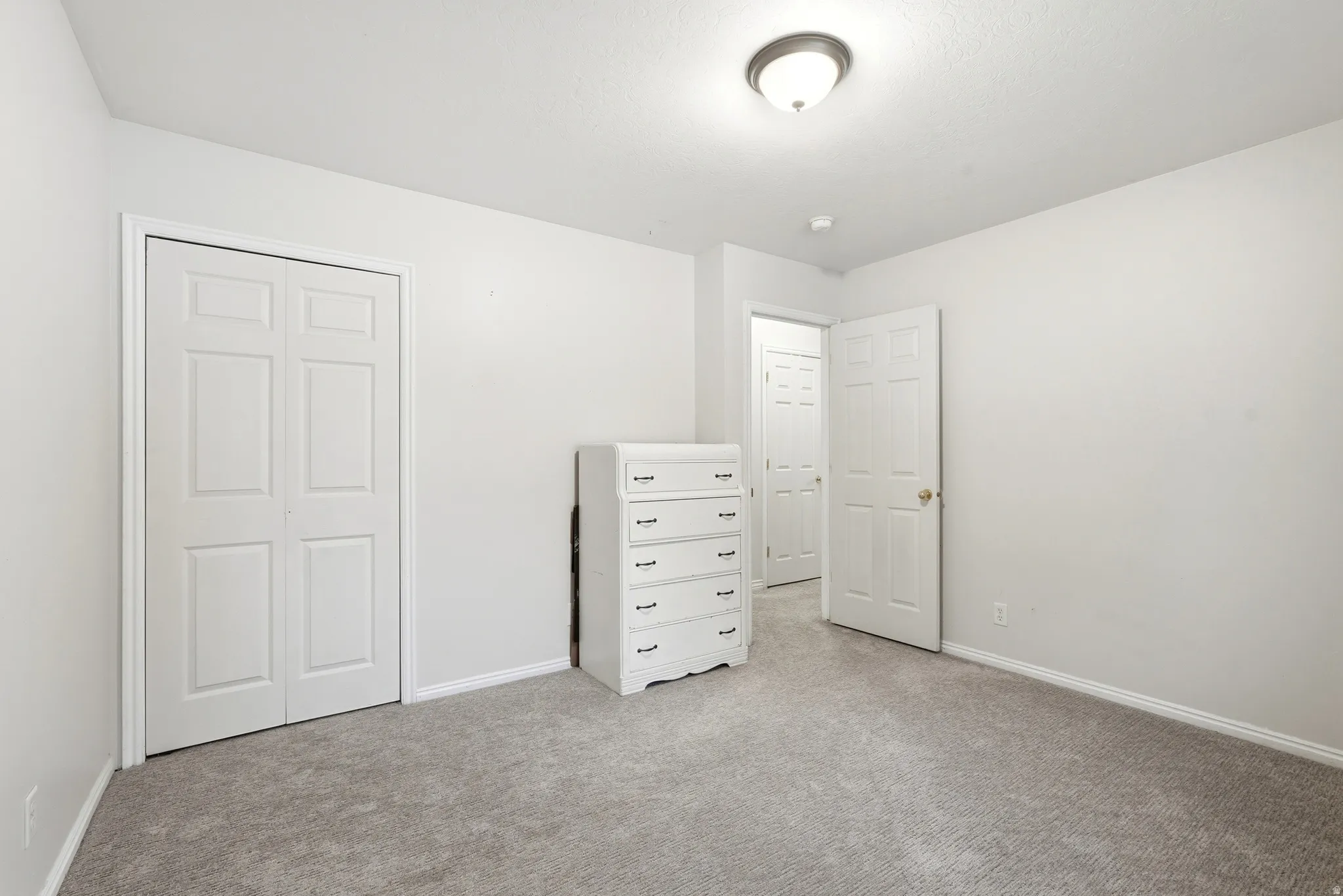 Neutral wall paint with textured ceiling, flush mount ceiling light, and gray carpet flooring