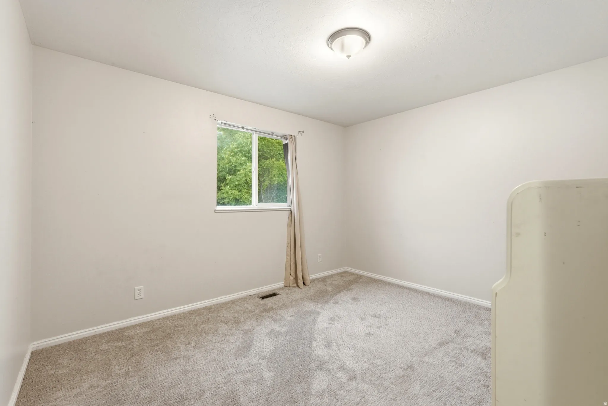 Neutral-toned interior room featuring light gray carpeting and white baseboards