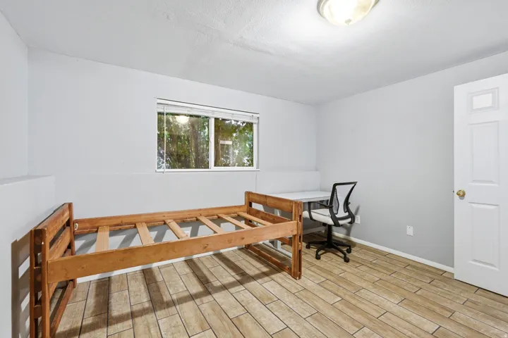 Spacious interior featuring light gray walls, wood-finish flooring, and a large window providing natural illumination