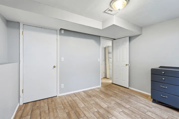 Wood-look tile flooring in a neutral-toned room featuring a built-in closet with white doors, a recessed ceiling light, and light gray walls