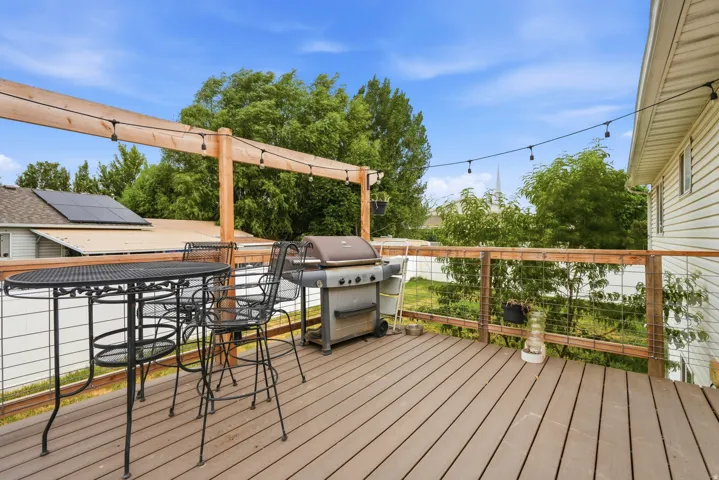 Spacious outdoor deck featuring composite wood-finish decking, wire railing, and overhead string lighting