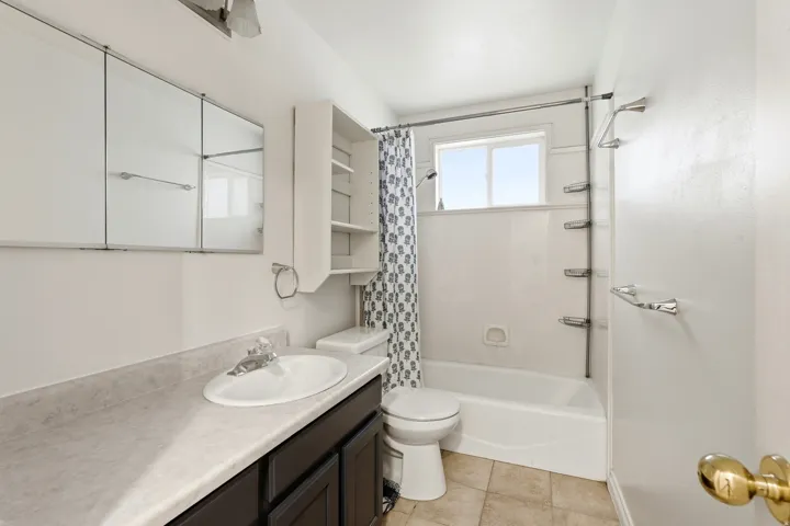 Full bathroom featuring a single vanity with dark cabinetry, an integrated sink, and a laminate countertop
