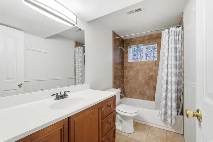 Bathroom featuring a single vanity with wood-finish cabinetry, white countertop, and integrated sink