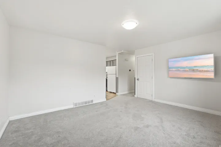 Bright interior space featuring light gray carpeting, white painted walls, and white baseboards