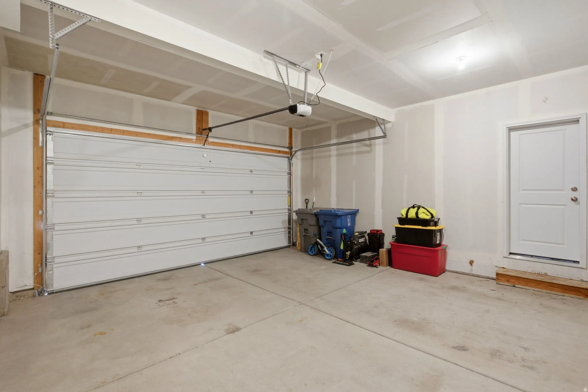 Spacious two-car garage featuring a concrete floor, white panel garage door, and interior access door