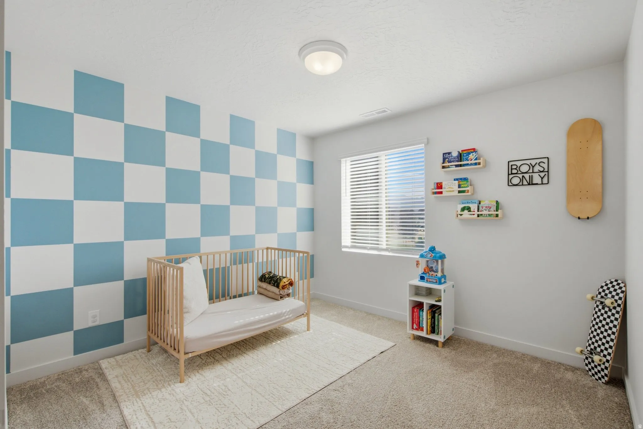 Bedroom featuring a checkered accent wall, carpet flooring, a window with blinds, and a flush mount ceiling light