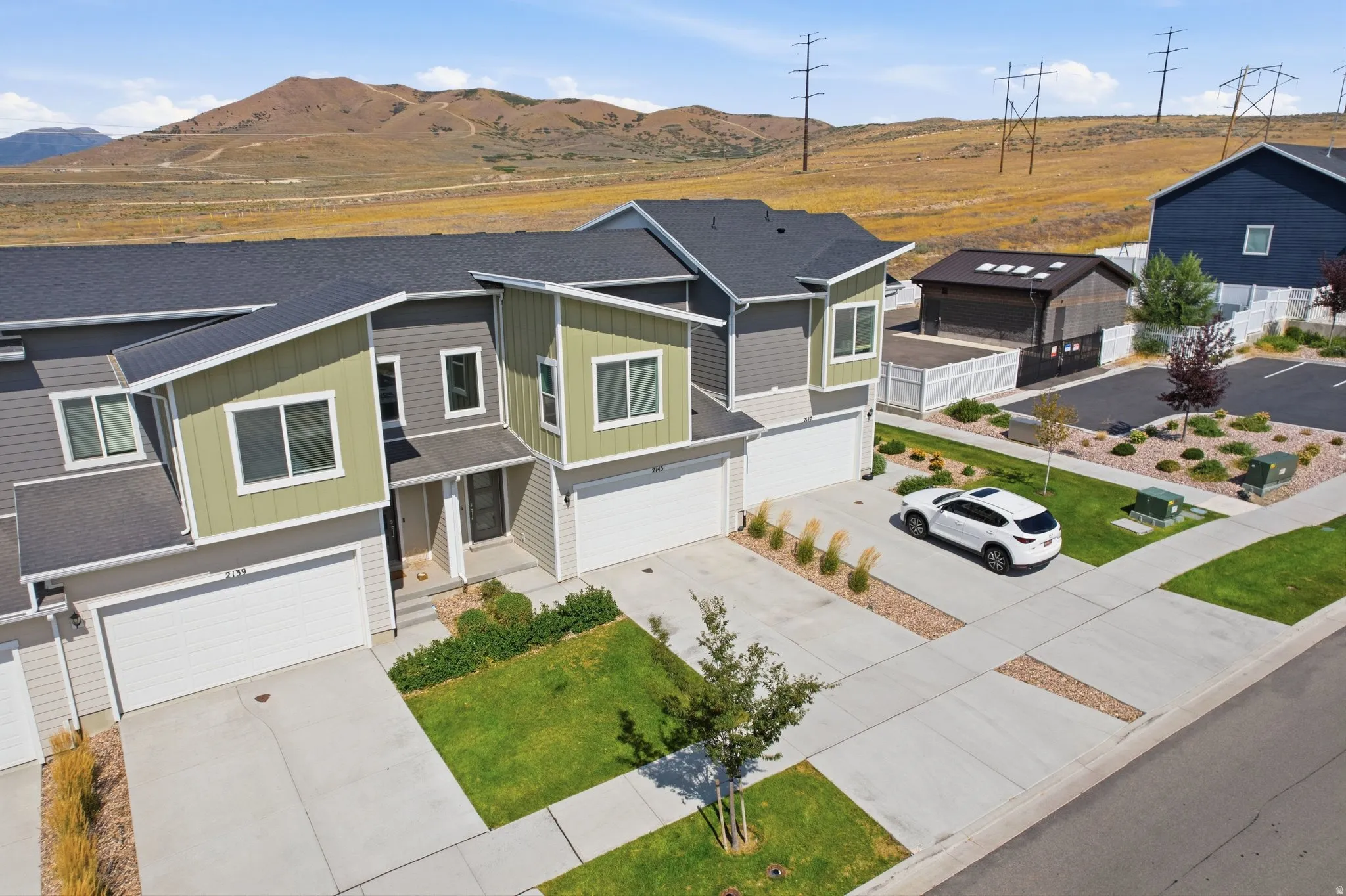 Contemporary townhomes featuring multi-toned siding, attached garages, and a paved driveway