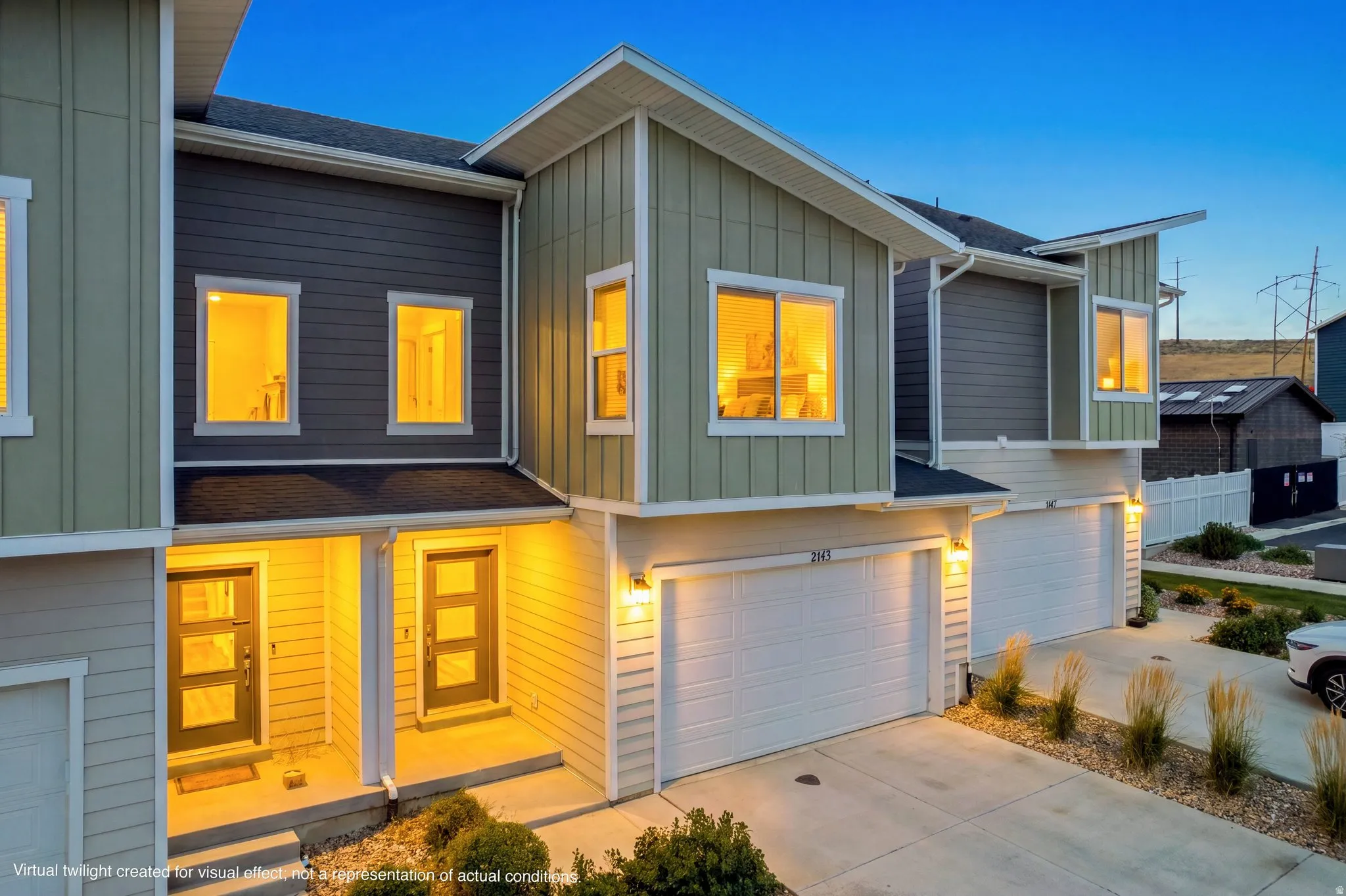 Contemporary townhome facade featuring a two-car garage, distinct entryway with modern door, and multi-tone siding
