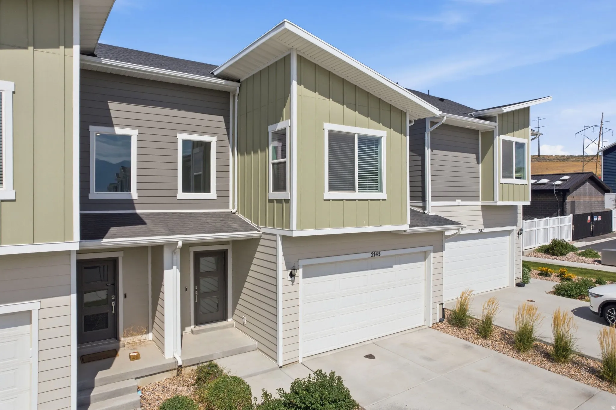 Contemporary townhome exterior featuring multi-toned siding, white trim, and a prominent attached garage with a white door
