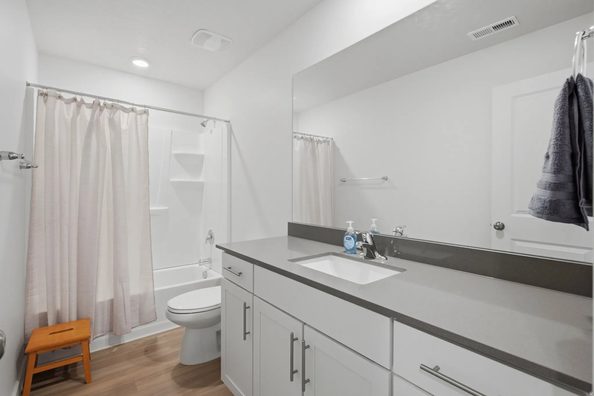 Bathroom featuring a single vanity with an integrated sink, a gray countertop, and white cabinetry