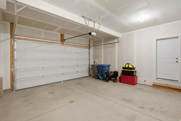 Spacious two-car garage featuring a concrete floor, white panel garage door, and interior access door