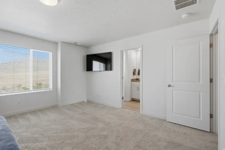 Carpeted room with a large window featuring horizontal blinds and a mountain backdrop