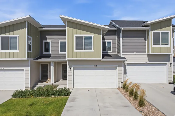 Contemporary townhome exterior featuring multi-toned siding, a front entry, an attached garage, and a concrete driveway