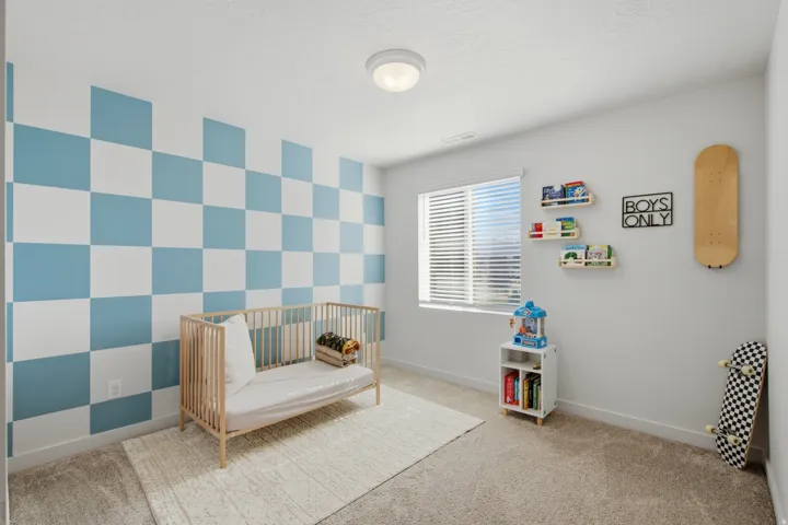 Bedroom featuring a checkered accent wall, carpet flooring, a window with blinds, and a flush mount ceiling light