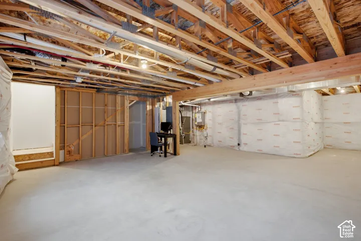 Spacious unfinished lower level featuring exposed wood joists, concrete flooring, insulated perimeter walls, and framed interior walls