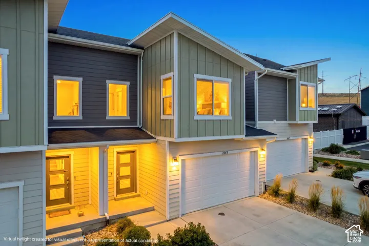 Contemporary townhome facade featuring a two-car garage, distinct entryway with modern door, and multi-tone siding