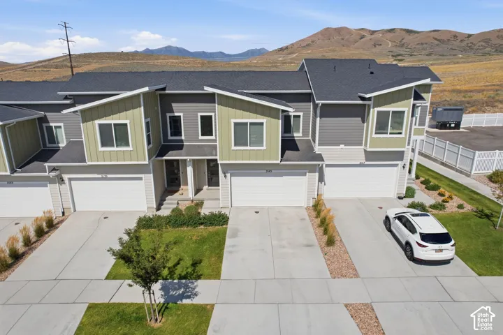 Contemporary townhome exterior featuring multi-toned siding, attached single-car garage, concrete driveway, and front landscaping