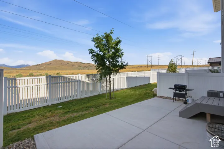 Concrete patio with a composite deck extension, white picket fencing, and a grassy yard area
