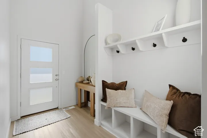 Entryway featuring a white door with three frosted glass panels, wood-finish flooring, and a built-in bench with integrated cubby storage