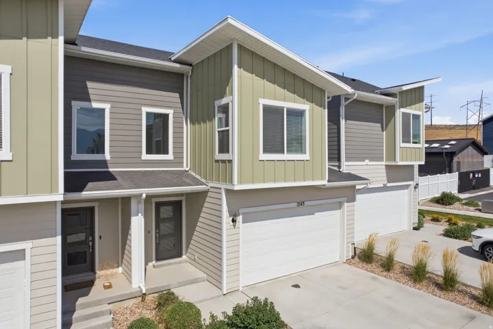 Contemporary townhome exterior featuring multi-toned siding, white trim, and a prominent attached garage with a white door