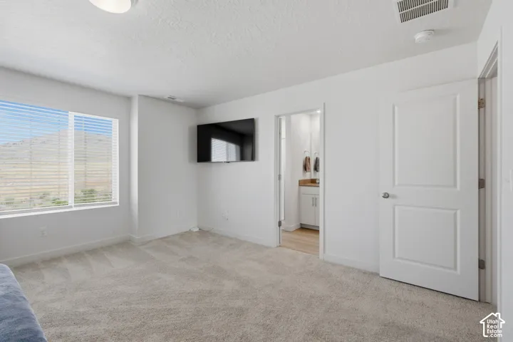 Carpeted room with a large window featuring horizontal blinds and a mountain backdrop