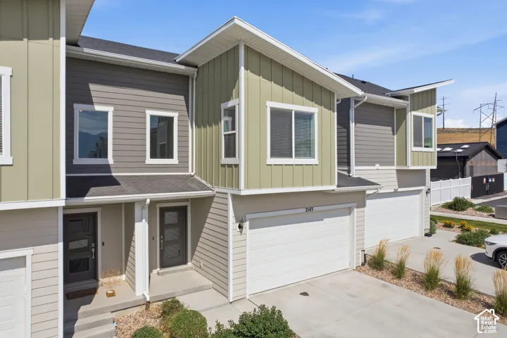 Contemporary townhome exterior featuring multi-toned siding, white trim, and a prominent attached garage with a white door