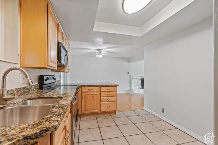 Kitchen featuring warm-toned cabinetry, granite-patterned countertops, and a stainless steel sink with a high-arch faucet