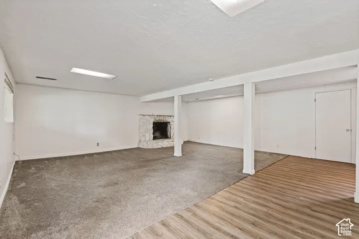 Spacious room featuring a stone fireplace, recessed lighting, and a combination of wood-finish flooring and carpet