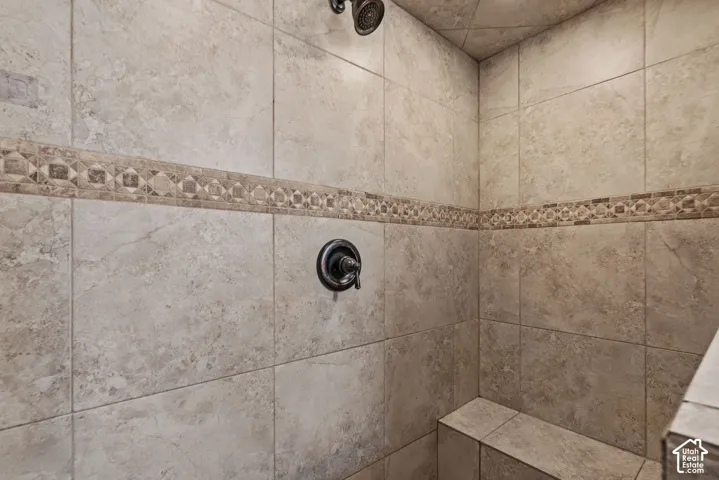 Tiled shower enclosure featuring a decorative mosaic accent band, oil-rubbed bronze showerhead, and a built-in bench