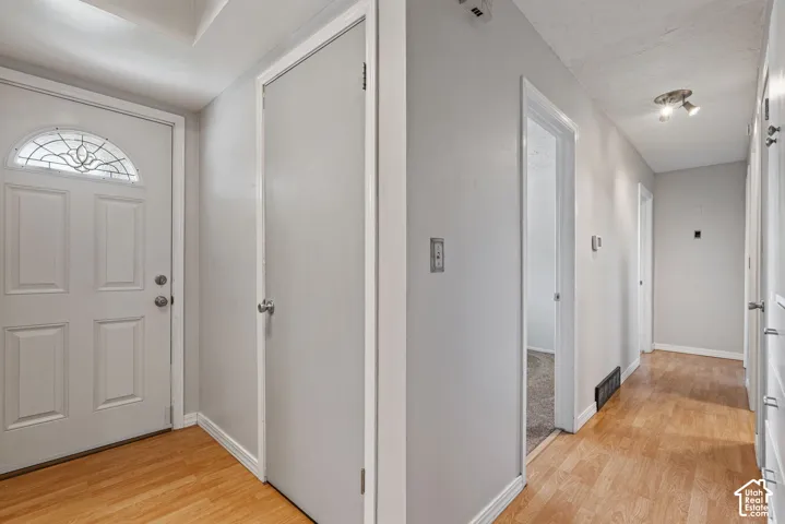 Entryway featuring wood-finish flooring, a white paneled door with decorative glass, and a closet with a solid white door