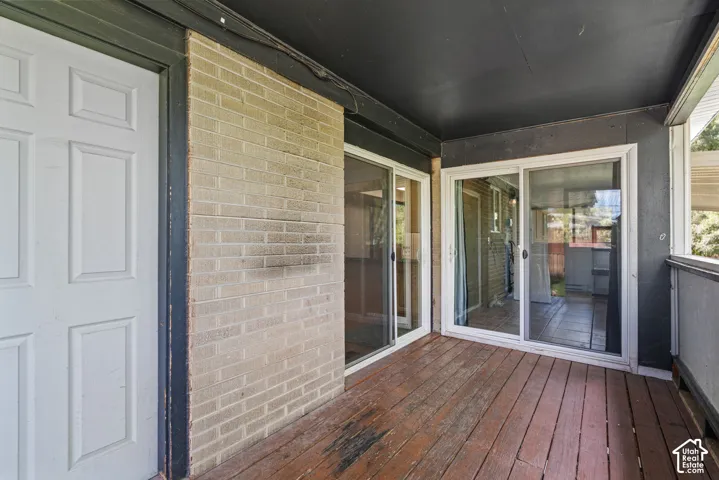 Covered patio area featuring wood-finish flooring, brick exterior siding, and multiple glass sliding doors