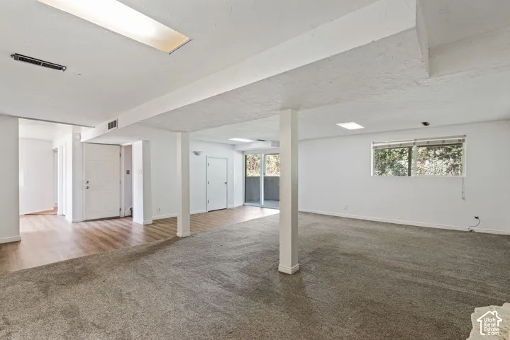 Expansive interior space featuring distinct carpet and wood-finish flooring areas