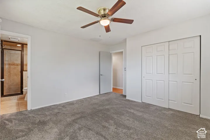 Bedroom featuring textured gray carpeting, white walls, and a ceiling fan with light fixture