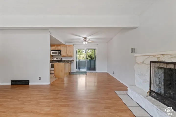 Open concept living area featuring wood-finish flooring, a stone-clad fireplace with a hearth, and sliding glass doors leading to an outdoor space