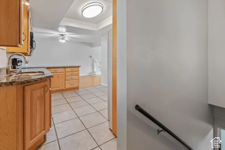 Kitchen area featuring wood cabinetry with a sink, granite countertops, and tile flooring