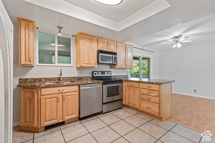 Kitchen featuring wood cabinetry, granite-style countertops, stainless steel appliances, and tile flooring