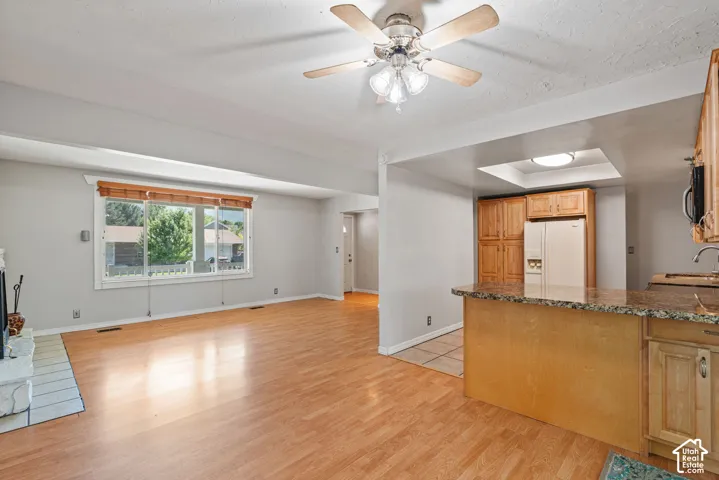 Spacious living area featuring wood-finish flooring, a ceiling fan with light fixture, and a large multi-pane window