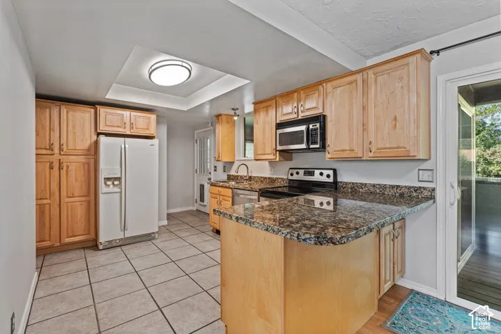 Kitchen featuring wood cabinetry, granite-style countertops, tile flooring, and a built-in microwave