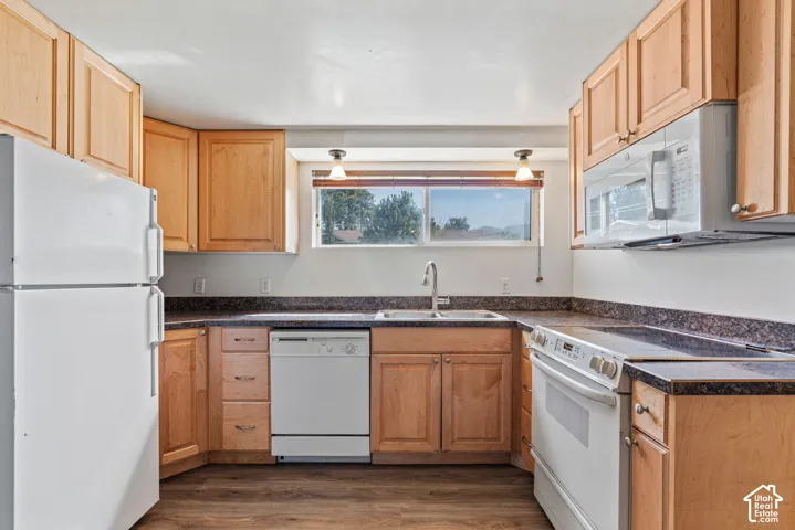 Kitchen featuring wood-finish cabinetry, dark speckled countertops, and wood-finish flooring