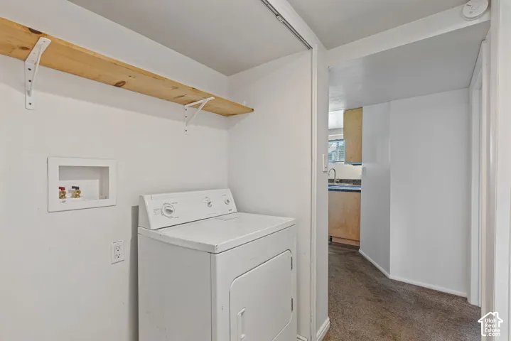 Dedicated laundry area featuring a wood-finish shelf, white walls, and a visible laundry hookup