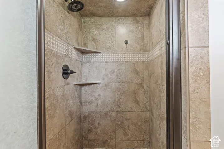 Tiled shower enclosure featuring a mosaic accent band, two built-in shelves, and a matte black shower head and control