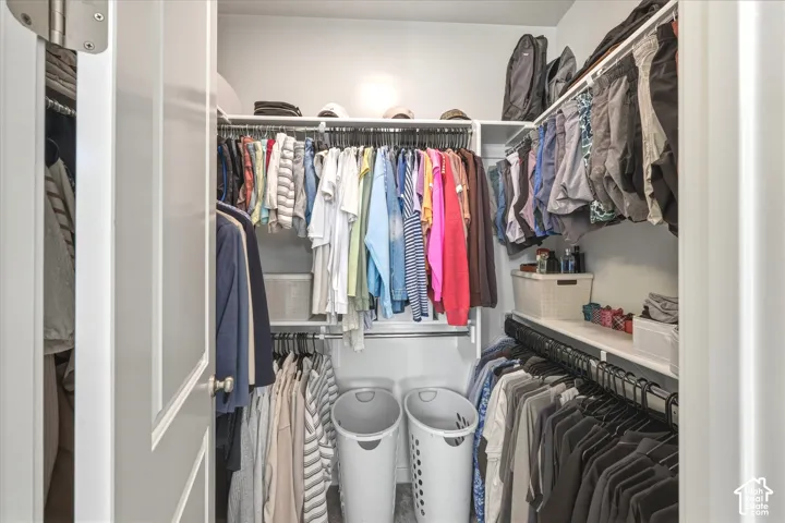 Walk-in closet featuring white built-in shelving, multiple hanging rods, and light gray wall paint