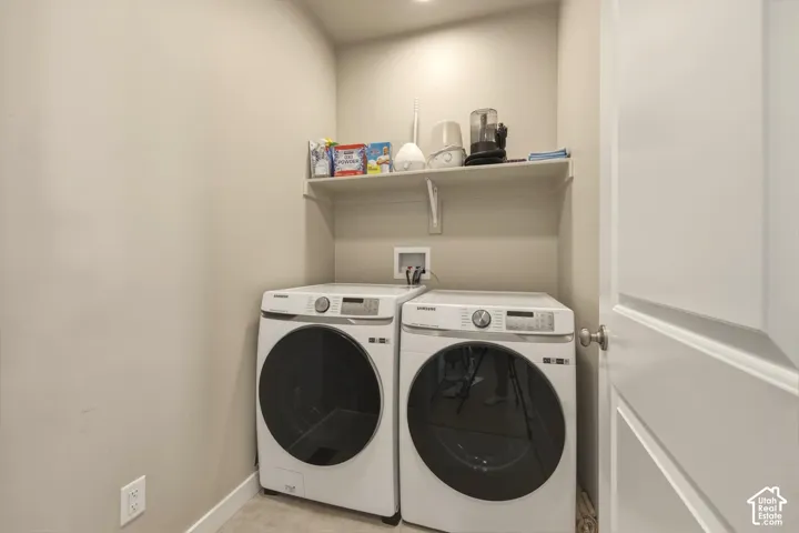 Dedicated laundry area featuring a wall-mounted shelf, front-loading washer and dryer hookups, and neutral wall tones
