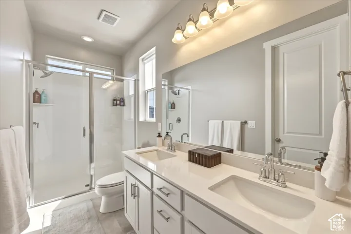 Bathroom featuring a dual vanity with undermount sinks, light-toned countertops, and chrome fixtures