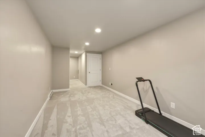 Spacious carpeted room featuring recessed lighting, a neutral color palette, white baseboards, and a white two-panel interior door