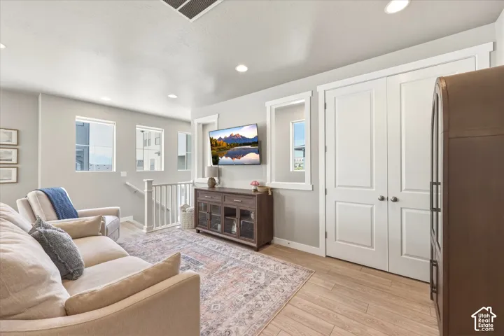 Living area featuring light wood-finish flooring, recessed lighting, and crisp white trim