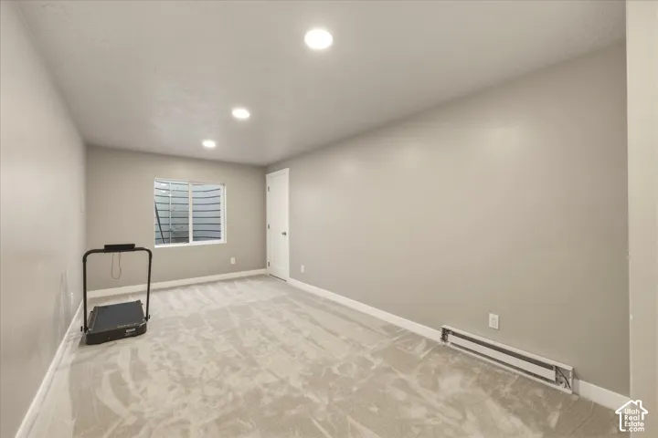 Expansive room featuring light gray walls, plush carpet flooring, and recessed ceiling lighting