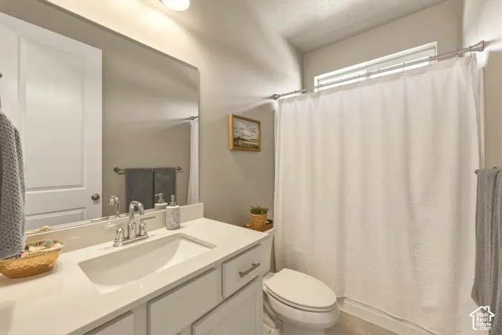 Bathroom featuring a single vanity with an integrated sink and light-colored countertop, chrome faucet, wall-mounted mirror, and a full shower/tub combination with a window above